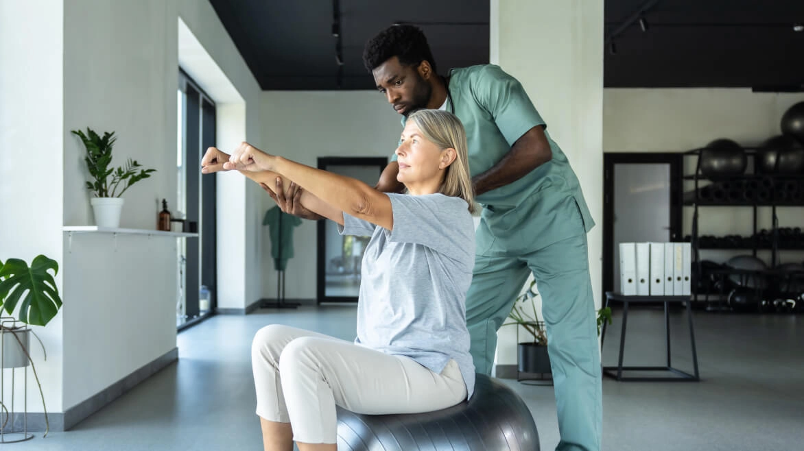 Woman on exercise ball undergoing physical therapy