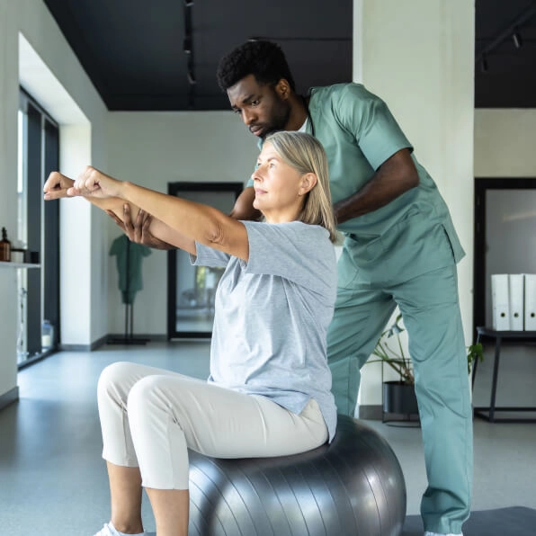 Woman on exercise ball undergoing physical therapy