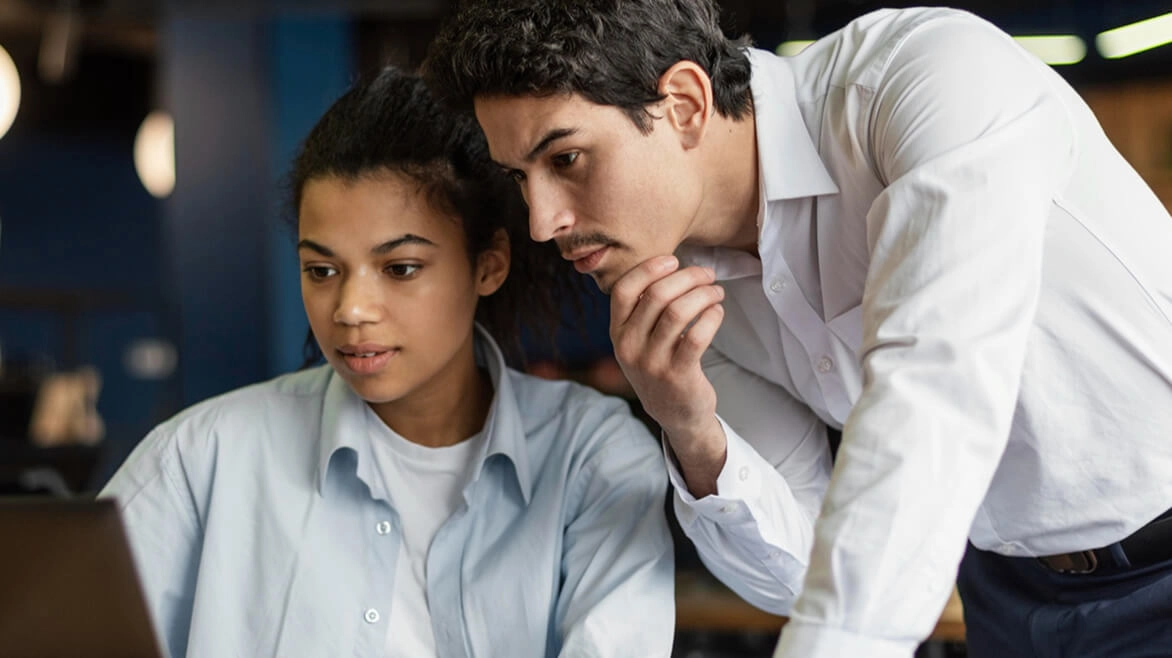 Man looking over shoulder of woman on laptop