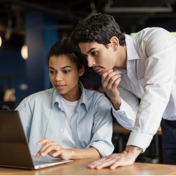 Man looking over shoulder of woman on laptop